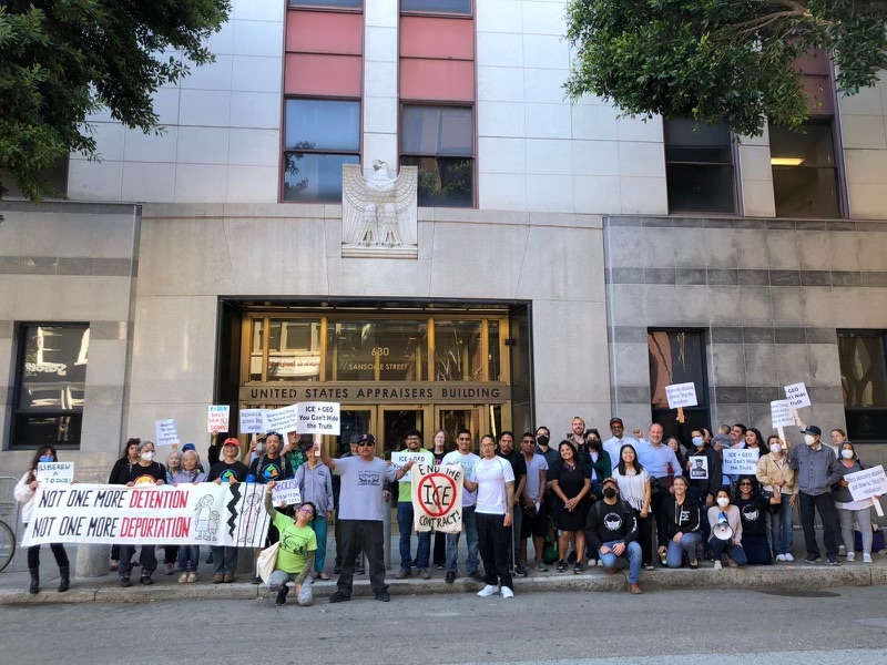 Grupo de personas con pancartas afuera de un edificio gubernamental