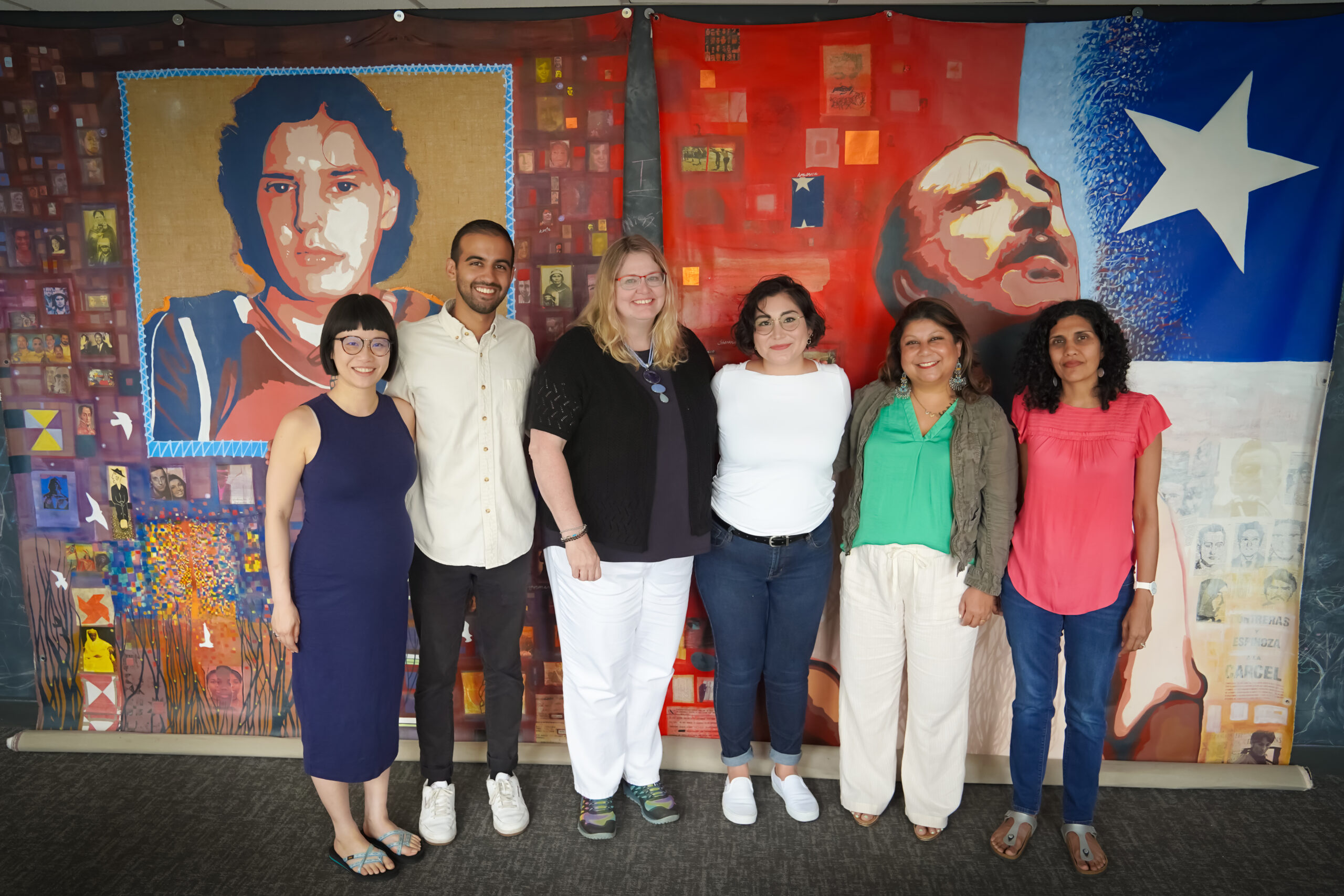 A group of people standing in front of a colorful canvas