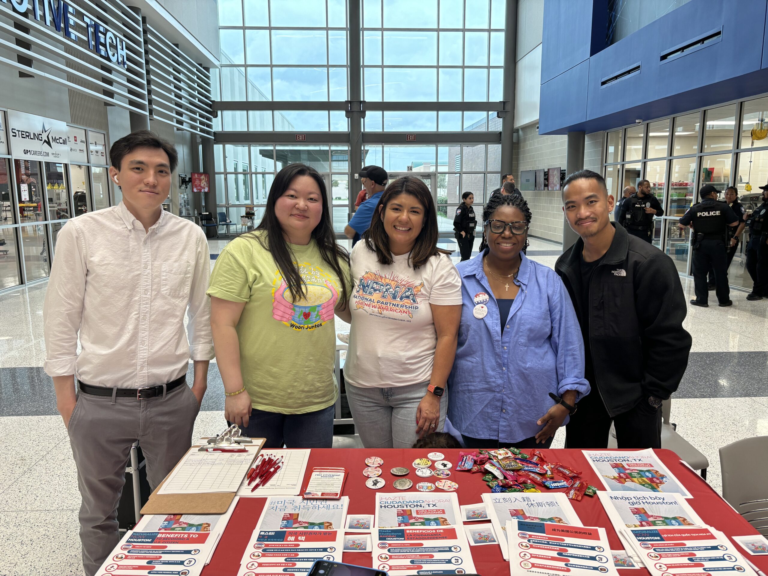 5 people standing behind a table with a red tablecloth and flyers