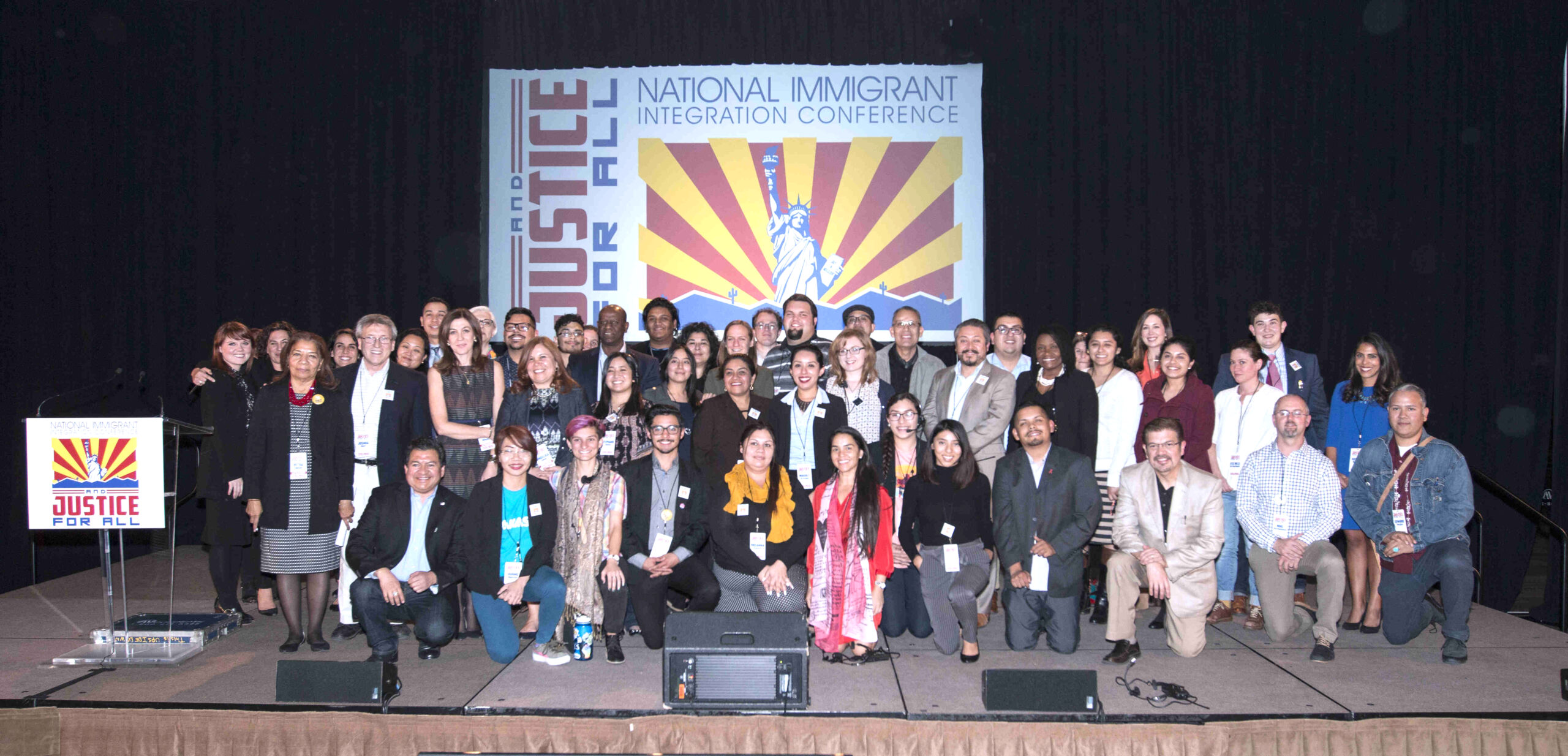 Group of people gathered in front of a banner that says National Immigrant Integration Conference 