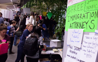 People at a fair next to a sign that reads "free immigration attorneys"